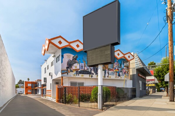 A building with a mural, a large billboard, and a gated entrance. - Rodeway Inn & Suites North Hollywood Burbank Airport - Universal Area (North Hollywood)