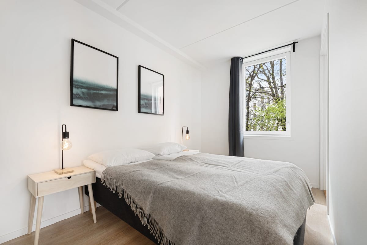 Une chambre à coucher moderne, avec un lit, des tables de chevet et deux lampes fixées au mur.