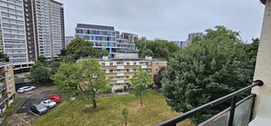 Una zona residencial con edificios de apartamentos de varios pisos, un estacionamiento con coches y árboles verdes.