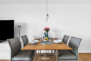 A modern dining area with a wooden table, grey upholstered chairs, and a vase with flowers.