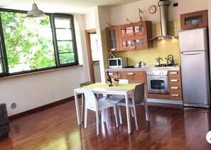 A modern kitchen with wooden cabinets, a refrigerator, a microwave, and a dining table with chairs.
