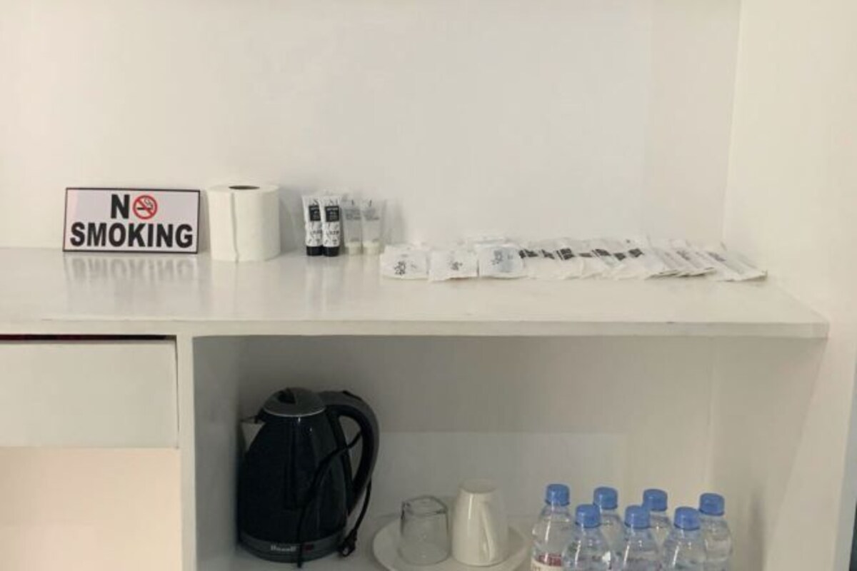 A hotel room with a 'NO SMOKING' sign, a kettle, a coffee maker, and several bottled waters on the counter.