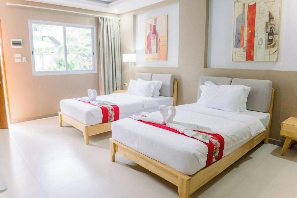 A hotel room with two beds, a window with curtains, and artwork on the walls.