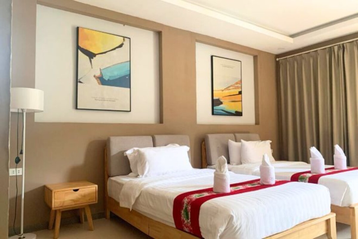 A hotel room with two beds, a bedside table, and artwork on the walls.