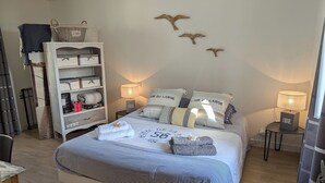 A neatly arranged bedroom with a large bed, bedside lamps, a wardrobe, and decorative wall art.