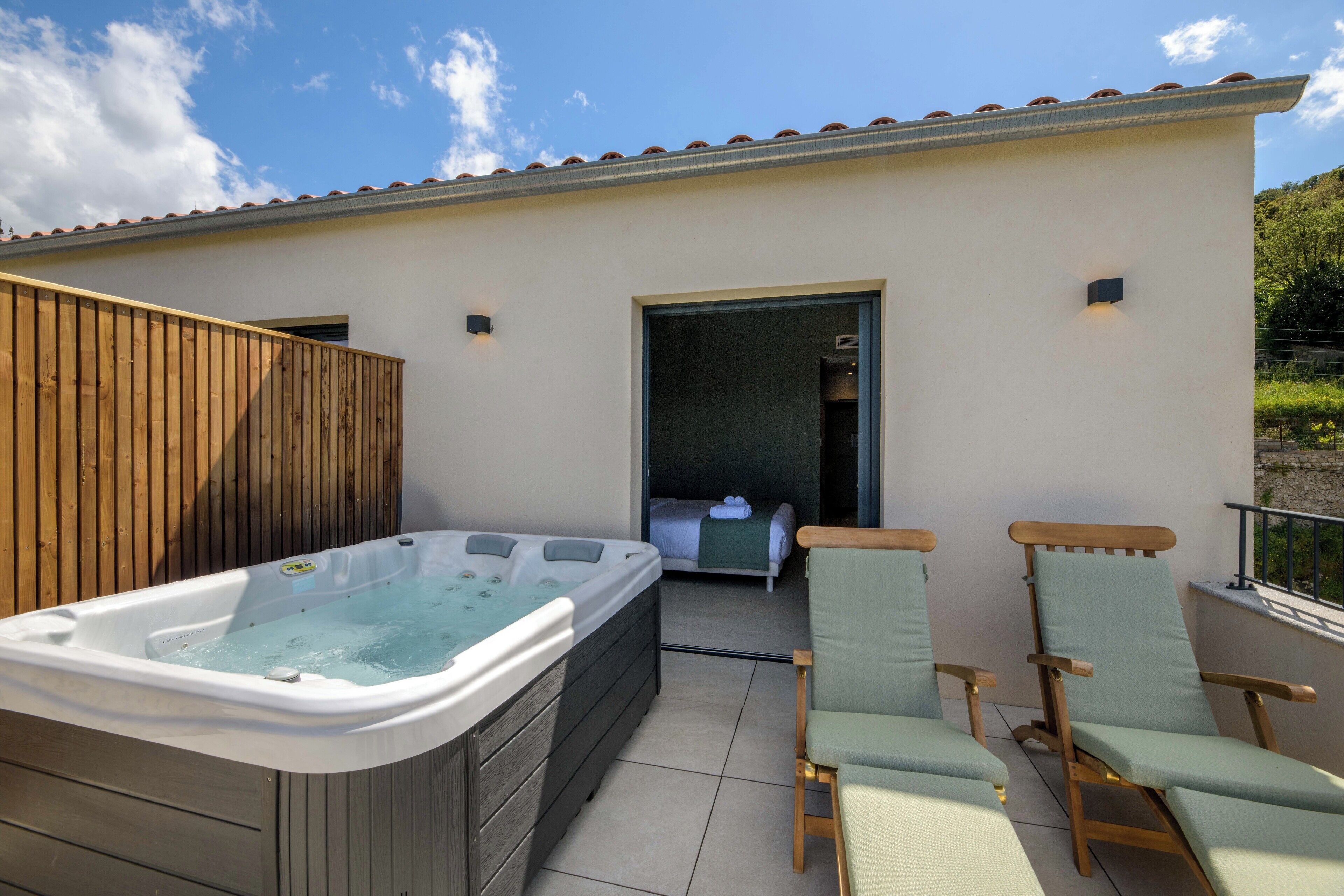 A spa area with a hot tub and two lounge chairs.