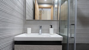 A modern bathroom with a rectangular sink, a glass shower enclosure, and a large mirror. - Studio Ag Ioannis m station 1 bed 2 pers by MPS (Vironas)