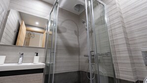 A modern bathroom with a glass-enclosed shower, a sink with a mirror, and a towel dispenser. - Studio Ag Ioannis m station 1 bed 2 pers by MPS (Vironas)