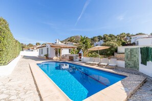 A swimming pool with lounge chairs, a barbecue area, and a view of the surrounding landscape.