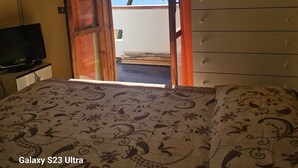 Une chambre à coucher comprenant un lit, une télévision, une commode et une fenêtre donnant sur des arbres et un plan d’eau.