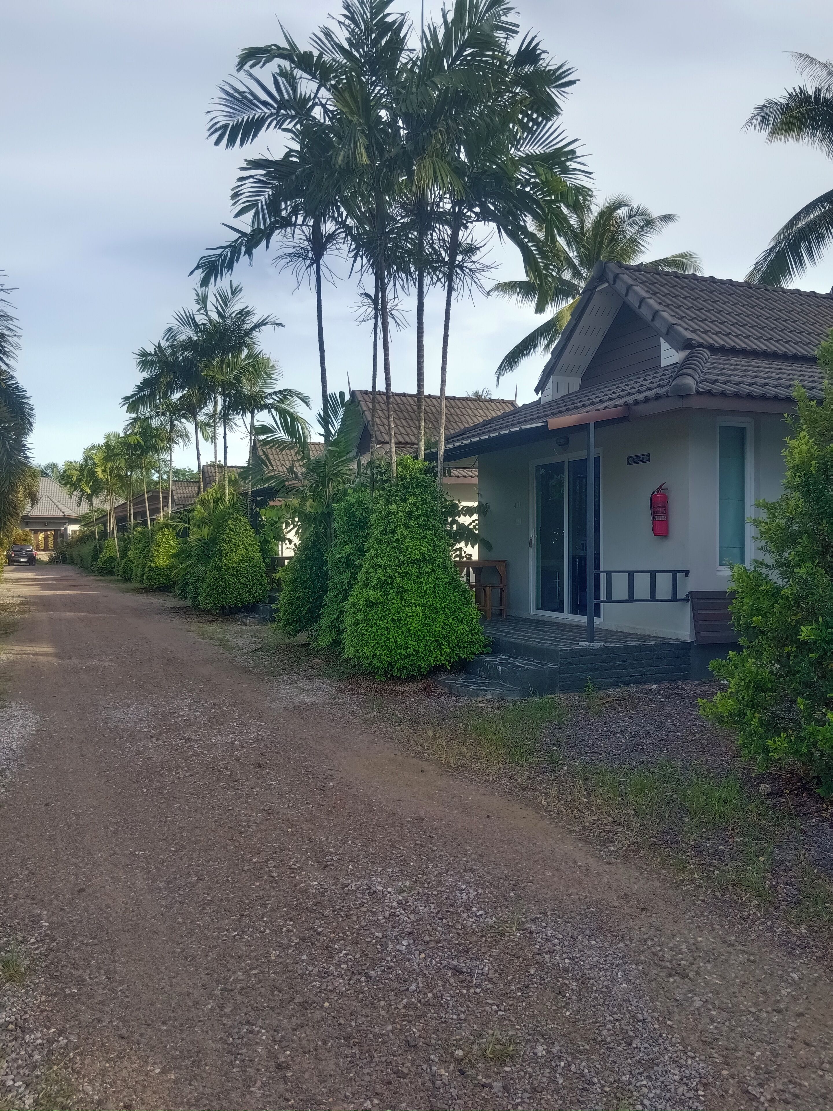 A residential area with a house featuring a tiled roof, a front porch, and a fire extinguisher mounted on the wall.