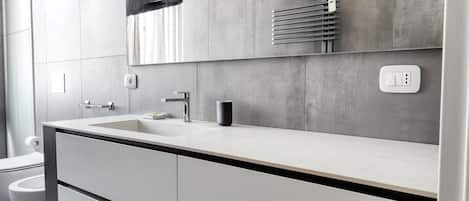Un baño moderno con un lavamanos grande, un espejo y un inodoro.