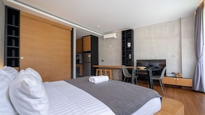 Una habitación de hotel moderna con una cama grande, un escritorio y una kitchenette.