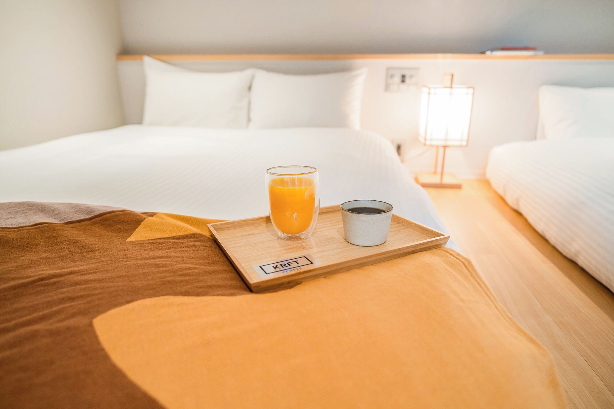 Quarto de hotel com uma cama, um recipiente com suco de laranja e uma xícara de café.