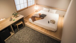 A compact hotel room with a bed, bedside table, lamp, and a small desk with a chair. - WAYFARER Gojo (Kyoto)