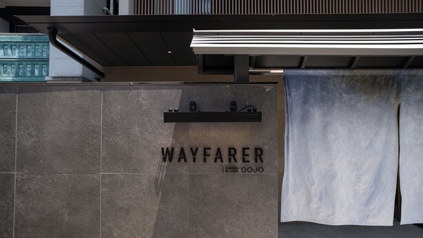 A stone wall with the text "WAYFARER" and "POWERED BY KOJI" indicating a brand or location. - WAYFARER Gojo (Kyoto)