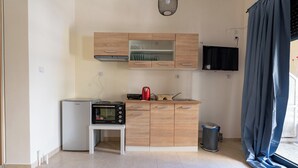 A compact kitchen with a microwave, a small refrigerator, and wooden cabinets. - Ag. Ioannis m. station 1 bed for 2 pers by MPS (Vironas)