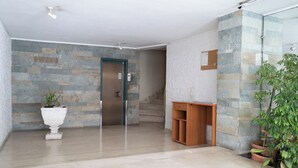 A modern lobby with a stone wall, a wooden bench, a potted plant, and a staircase. - Ag. Ioannis m. station 1 bed for 2 pers by MPS (Vironas)