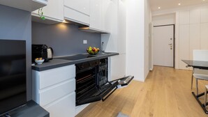 A modern kitchen with white cabinets, a black countertop, and a built-in oven. - notaMi - Monte Ceneri Suite (Milan)