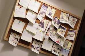 A corkboard with pinned notes and photographs, likely used for organizing information or memories. - Lotus Home Corner & Rooftop (Phu Quoc)