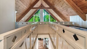 A wooden staircase leading to a balcony with a view of greenery.