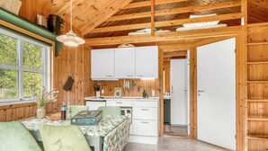 A cozy kitchen with wooden beams, white cabinets, and a dining area with a table and chairs.