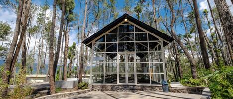 A glass-roofed building surrounded by tall trees.