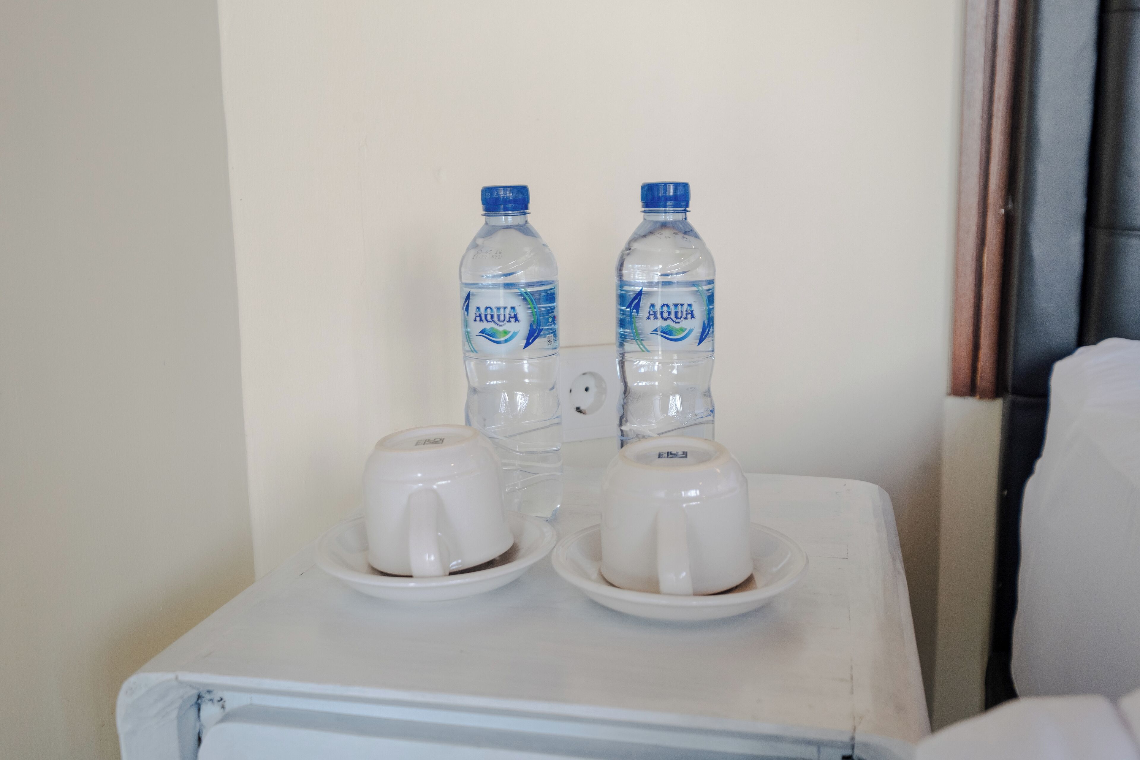 A small table with two water bottles and two white cups on saucers.