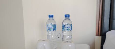A small table with two water bottles and two white cups on saucers.