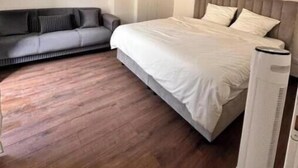 Een moderne slaapkamer met een bed, een bank en een elektrische kachel.
