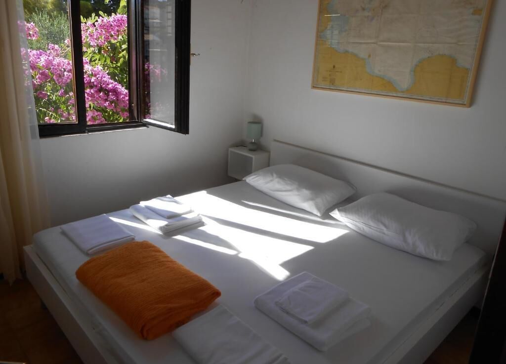 Un lit bien fait, avec des serviettes blanches et orange, une table de chevet avec une lampe et une carte accrochée au mur.