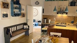 A cozy kitchen with wooden cabinets, a wooden dining table, and a bench. There are decorative items on the walls and a clock on the wall. - Holiday house Mia (Rogoznica)