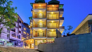 A multi-story hotel with balconies, a covered entrance, and potted plants. - Hotel Nirosha Manali (Manali)
