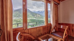 A wooden room with a large window offering a view of a mountainous landscape. - Hotel Nirosha Manali (Manali)