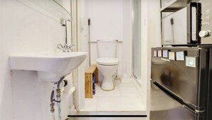 A compact bathroom with a white sink, toilet, and a black refrigerator. - wellness studio Nottingham city centre (Nottingham)