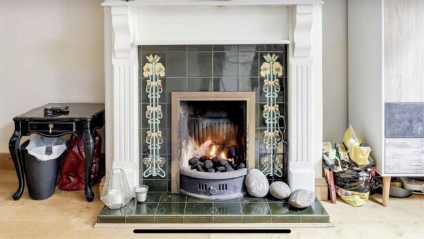 A fireplace with a fire, a table with a bag, and a trash bin. - wellness studio Nottingham city centre (Nottingham)