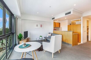 Een modern appartement met een zithoek, een eettafel, een bank, een keuken en een balkon met uitzicht.