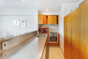 A modern kitchen with stainless steel appliances, wooden cabinets, and a tiled backsplash.