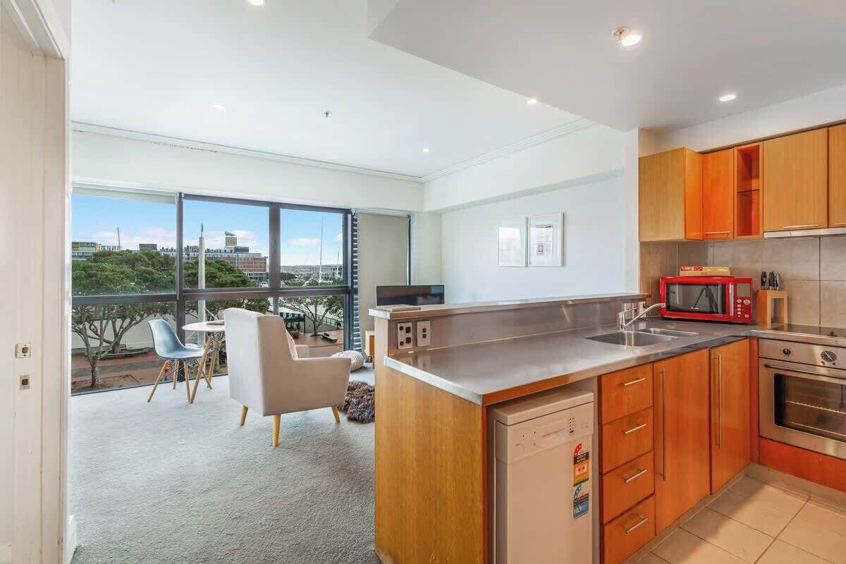 A modern kitchen with wooden cabinets, a stainless steel sink, and a built-in oven.