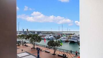 A marina with boats docked, a pedestrian walkway, and a clear sky.