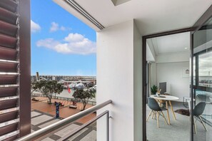 Un balcon donnant sur un port de plaisance, un coin repas avec une table et des chaises, et un intérieur moderne agrémenté d’une porte vitrée.