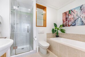 Une salle de bain moderne avec une douche à parois de verre, des toilettes, un lavabo et une baignoire.