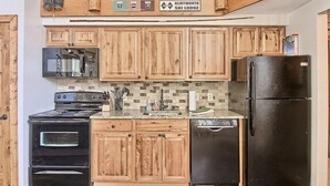 Una cocina con armarios de madera, estufa, microondas, refrigerador y lavavajillas.