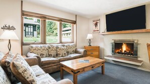 A cozy living room with a fireplace, a sofa set, and a television. - Ramshead: Main Floor: Ski in Ski Out (Boyne Falls)