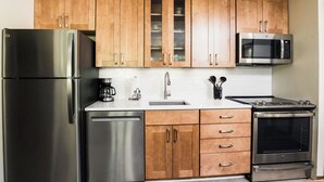 A modern kitchen with stainless steel appliances, wooden cabinets, and a white countertop. - Ramshead: Main Floor: Ski in Ski Out (Boyne Falls)