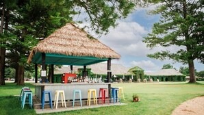 A thatched-roof outdoor bar area with colorful stools and a counter. - Ramshead: Main Floor: Ski in Ski Out (Boyne Falls)