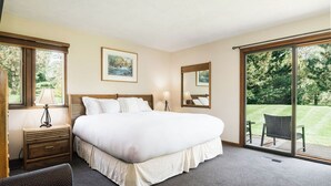 A hotel room with a large bed, a desk, a chair, and a sliding glass door leading to a balcony. - Ramshead: Main Floor: Ski in Ski Out (Boyne Falls)