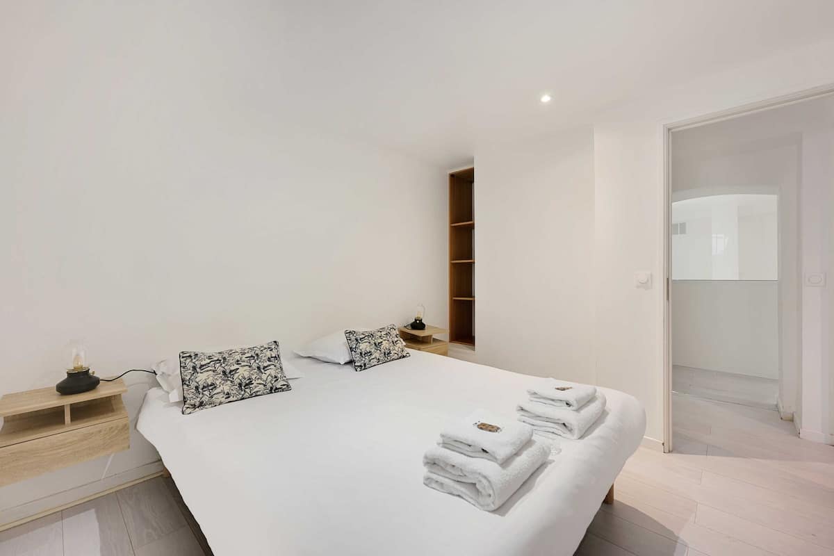Ein modernes Hotelzimmer mit einem großen Bett, Nachttischen, einem Beistelltisch und einem Kleiderschrank.
