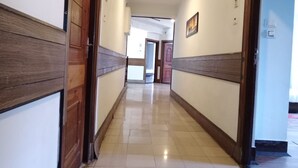 A hallway with wooden paneling and a tiled floor, leading to a room with a door and a window. - Hotel Dew Pond  (Gangtok)