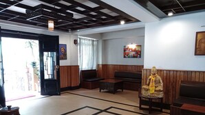 A lobby with a wooden bench, a statue, and a patterned floor. - Hotel Dew Pond  (Gangtok)
